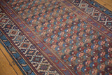 Staggered repeating floral motifs in navy, blush, and wine on an antique Caucasian Kuba runner.