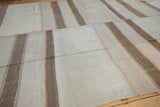 Patchwork kilim rug with ivory and pale coffee brown banded stripes, showing terracotta stitching.