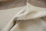 Folded vintage Turkish Kilim shows ivory and pale bronze banded texture with terracotta stitching.