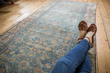 Distressed Malayer runner rug's allover Herati pattern in faded blue and terracotta, with legs.