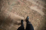 Distressed Oushak carpet displaying worn beige, moss green, and blush tones from above.