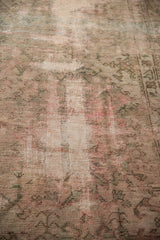 Distressed Oushak rug texture with faded beige, blush, and moss green motifs.