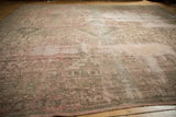 Distressed Oushak rug texture with muted beige, blush, and moss green pile.