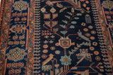 Close-up of a vintage Mehreban rug's navy pile showing stylized birds and delicate floral vinery.