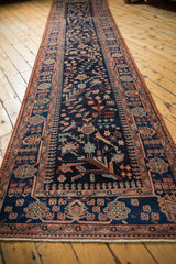 Perspective view of the vintage Mehreban runner's allover bird and floral pattern on a navy field.