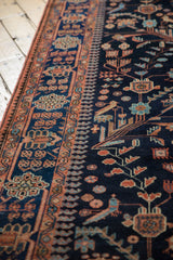 Detail of the Persian runner's navy field showing stylized birds and terracotta vinery.