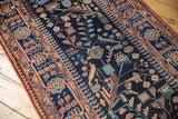 Stylized birds and delicate vinery in terracotta and sky blue on a hand-knotted navy pile.