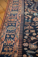 A detailed view of the Persian runner's terracotta border alongside the navy field's stylized bird motifs.