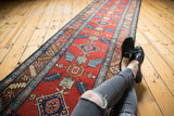 Brick red vintage Northwest Persian runner with repeating blue quatrefoil floral designs.