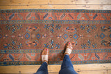 Heriz runner's bronze field, madder red border featuring serrated leaves, and blue motifs.