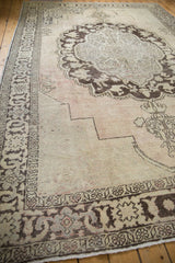 Vintage carpet corner with distressed pile and chocolate brown border patterns.