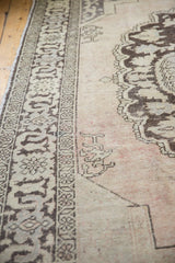 Distressed Oushak rug's chocolate brown border, antique ivory field with mostly even wear.