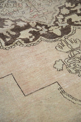 Distressed Oushak rug pile with blush tones, ivory field, and chocolate brown motifs.