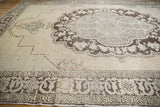 Distressed Oushak rug border showing chocolate brown motifs, antique ivory field, faint foundation.