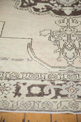 Vintage distressed Oushak carpet close-up: chocolate brown motifs on antique ivory, mostly even wear.