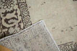 Distressed Oushak rug corner showing faint wear on pile and woven foundation.