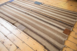 Stitched brown patch and tattered edge detail on the striped Moroccan Kilim.