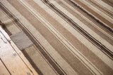 Textured striped Moroccan Kilim, featuring earthy brown and ivory bands, with a visible patch.