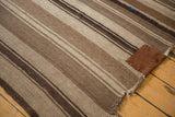 Vintage Moroccan Kilim with varied brown and ivory stripes, featuring a hand-stitched patch.