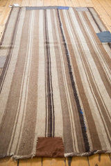 Vintage Moroccan Kilim close-up with brown, ivory stripes, a large patch, and blue darning.
