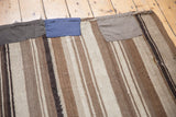 Blue and brown patched regions on a vintage Moroccan Kilim rug, showcasing striped brown and ivory weave.