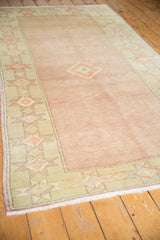Distressed Oushak border with pale seafoam green geometric starbursts and pale blush field.
