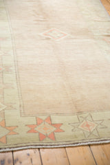 Pale blush distressed Oushak field with geometric starbursts on seafoam celadon border.