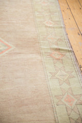 Low pile texture on a distressed Oushak rug, pale blush field and seafoam geometric starburst border.