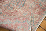 Folded corner of distressed Sparta carpet, showing worn pile, hand-knotted foundation, and blush tones.