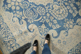 Distressed vintage Kerman carpet showing indigo blue floral vinery, wispy waves on beige.