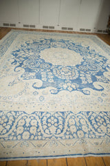 Distressed indigo blue floral vinery on the antique ivory border of a Persian Kerman rug.