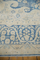 Distressed Kerman carpet featuring indigo blue floral border and wispy ivory curvilinear motifs.