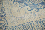 Vintage distressed Kerman rug corner, indigo blue floral border on antique ivory field.