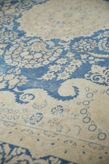 Distressed indigo blue and antique ivory floral vinery detail on a vintage Kerman carpet.
