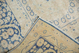 Distressed Kerman rug corner folded, revealing indigo floral motifs, secure edge binding, and reverse.
