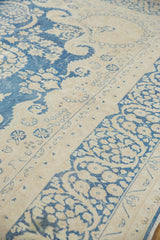 Distressed indigo blue floral vinery and antique ivory border of vintage Kerman carpet.