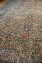 Textured close-up of distressed Tabriz showing faded teal scrolling arabesques and blush florals.