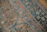 Distressed vintage Tabriz carpet with faded teal, blush floral arabesques on beige, foundation visible.