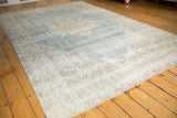 Distressed corner of vintage Oushak carpet, featuring pale denim blue and ivory scrolling vinery.