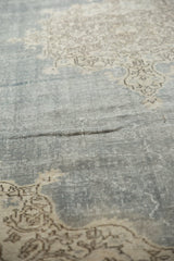 Distressed denim blue Oushak carpet texture showing worn pile and faint scrolling vinery.