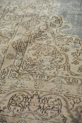 Distressed texture of a vintage Oushak rug with beige scrolling vinery and blue field.