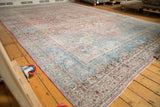 Corner detail of distressed Persian Meshed rug, showing faded dusty teal, pale raspberry floral vinery.