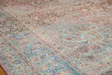 Distressed vintage Persian Meshed carpet close-up, showing faded pink, blue vinery and even wear.