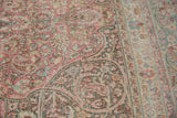 Distressed Meshed carpet detail: ornate scrolling vinery, blush, and dusty teal hues.