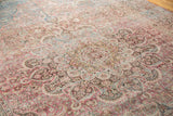 Worn vintage Meshed rug pile with detailed floral scrollwork in soft raspberry, teal, and ivory.