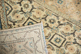 Distressed vintage Mahal rug folded, showing faded Herati pattern and intricate hand-knotted reverse.