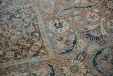 Distressed pile of vintage Mahal carpet with worn floral motifs and exposed foundation.