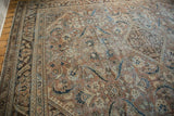 Distressed Vintage Mahal carpet corner with faded brown, ivory, and dark teal floral motifs and texture.