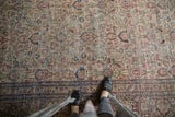 Textured distressed Khorassan carpet shows worn pile, traditional floral, and navy-red border.