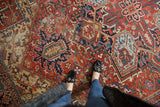 Heriz carpet, cherry red, blue, gold geometric floral patterns, with feet visible.
